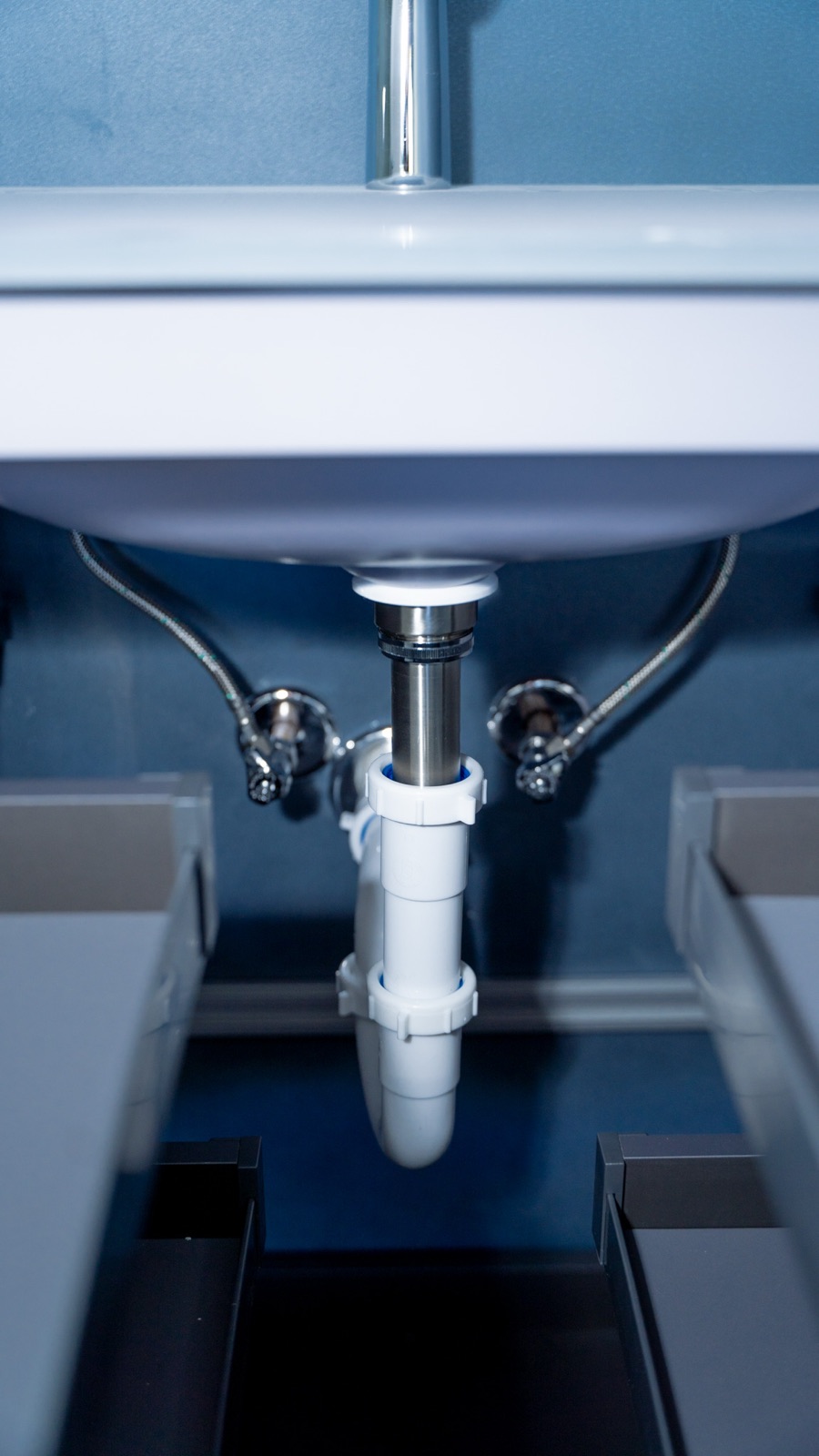 Under-sink plumbing with chrome drain and supply lines