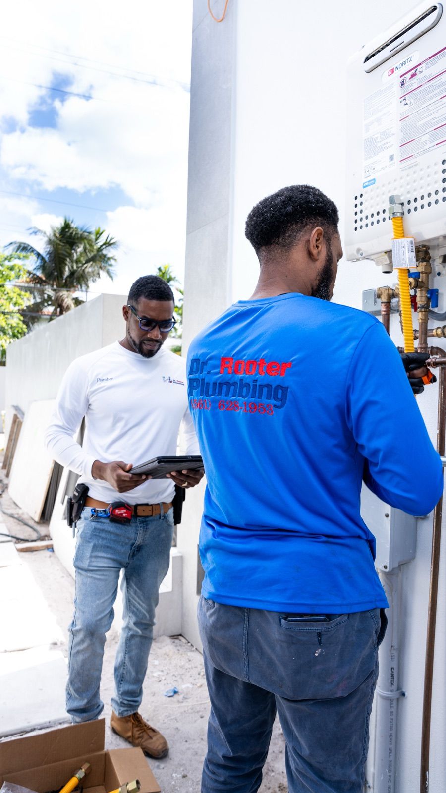 Two Dr. Rooter Plumbing technicians reviewing a tankless water heater installation